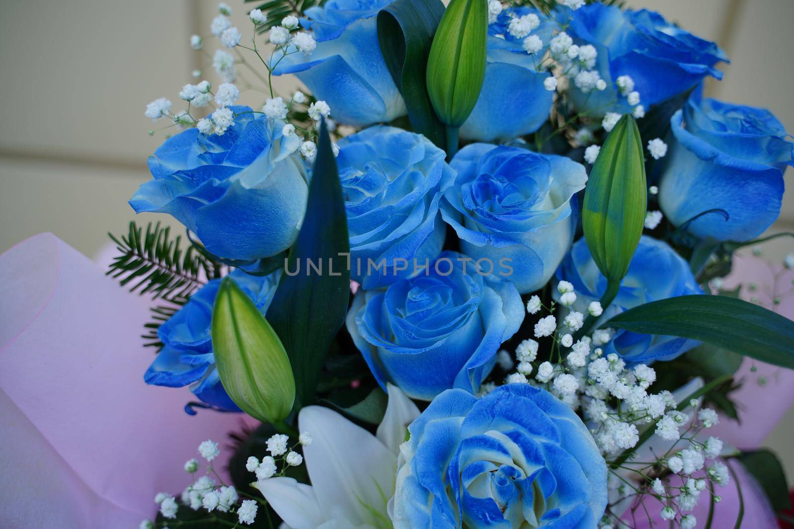 Close up of colorful bouquet of flowers. Flower composition of blue roses and white lilies in wrapping paper