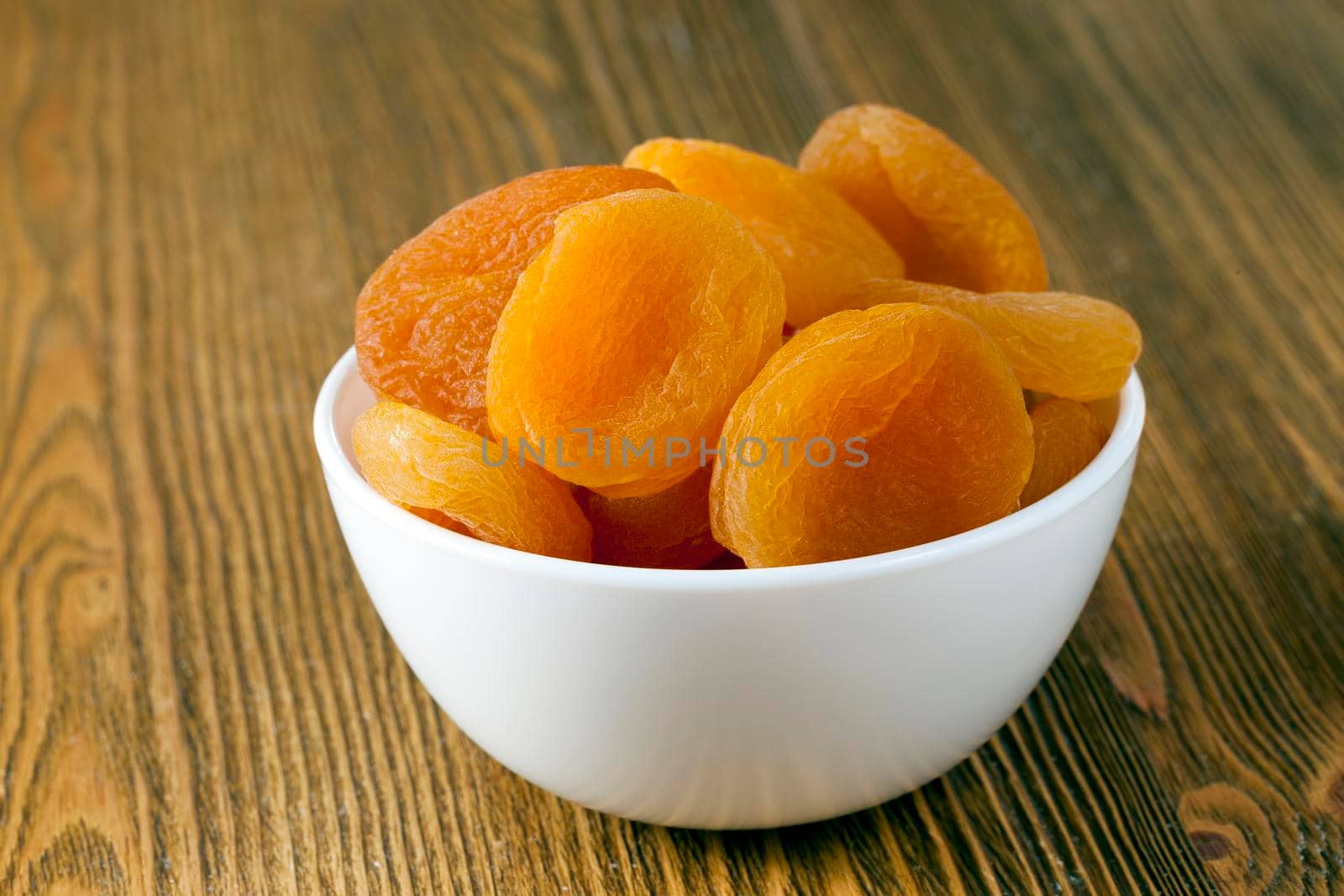 dry beautiful apricots in a bowl on a table, closeup in nature
