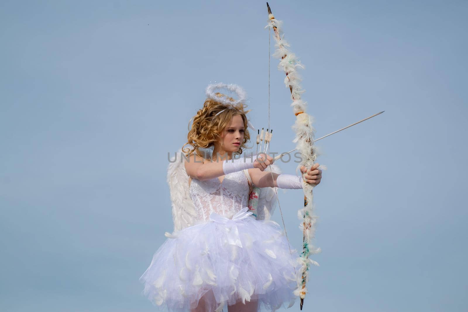 Pretty white little girl as the cupid with a bow and arrow congratulating on St Valentines day. Happy Valentines day. Cute little cupid shoots a bow by Tverdokhlib