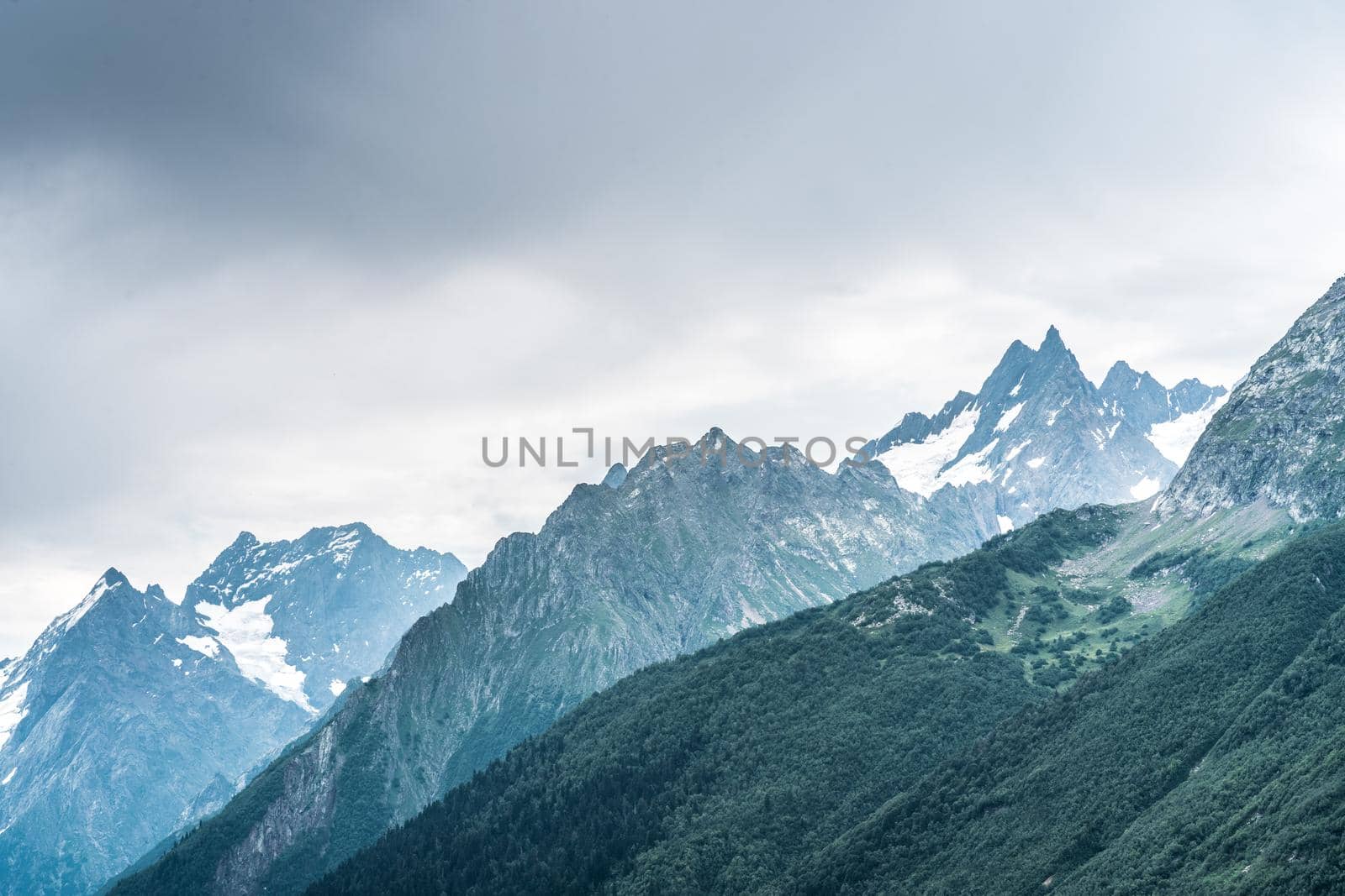 Mighty mountains with snow in cloudy weather.