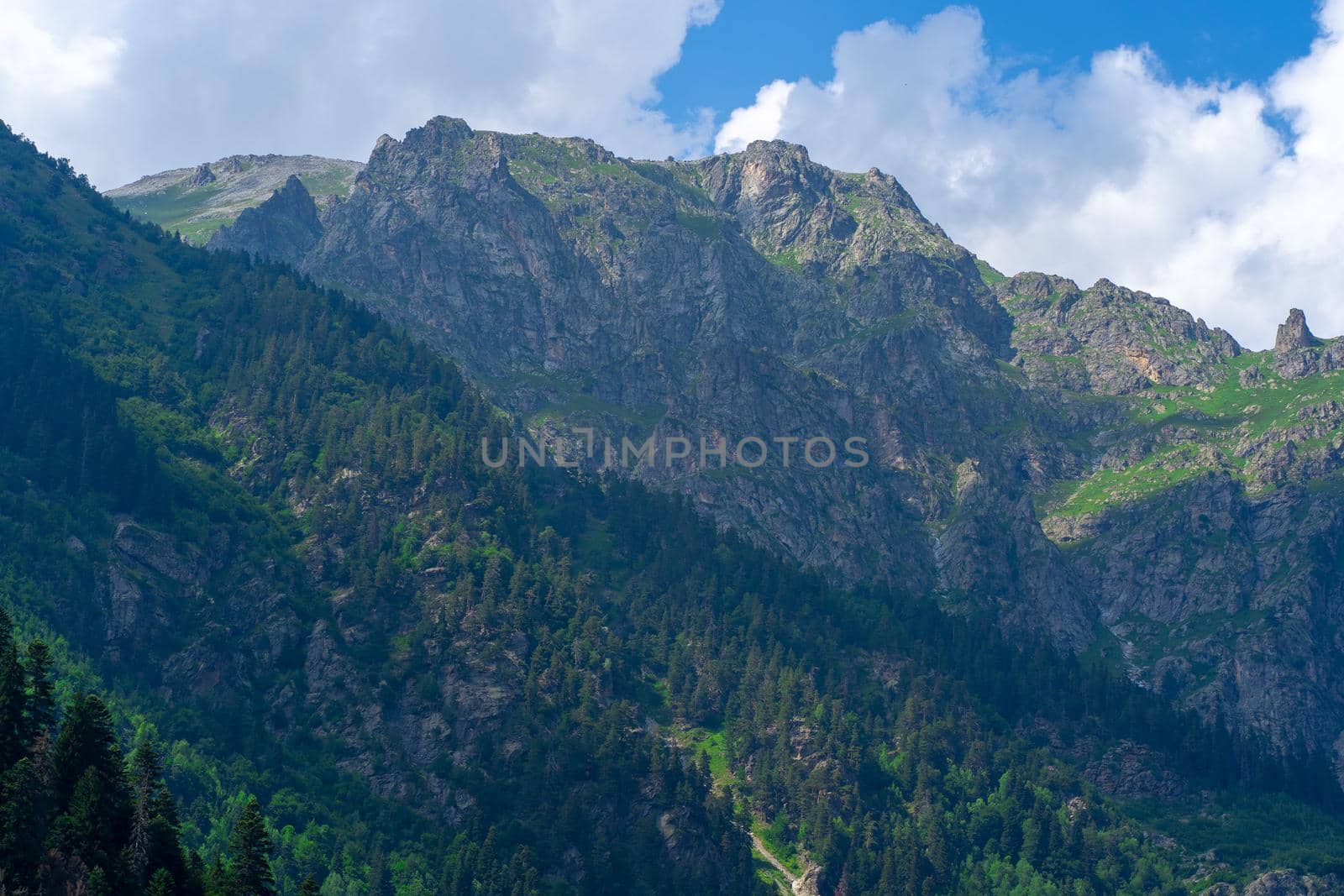 Peaks of magnificent rocks located against bright cloudy sky on sunny day in nature.