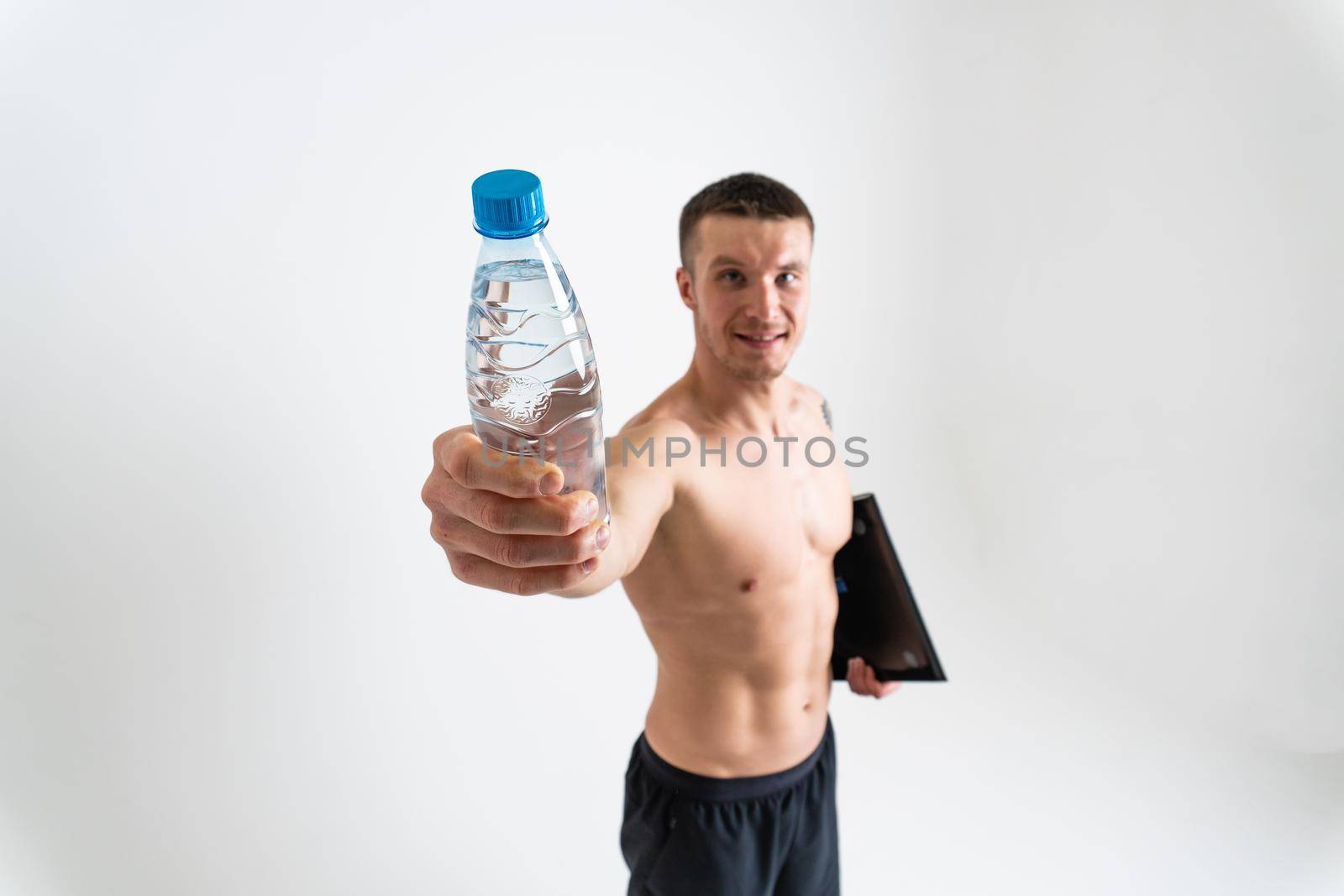 Male drink-water fitness is pumped with a towel on a white background isolated fitness muscular water healthy gym man sportive, sporty cardio. protein pace, caucasian one muscle