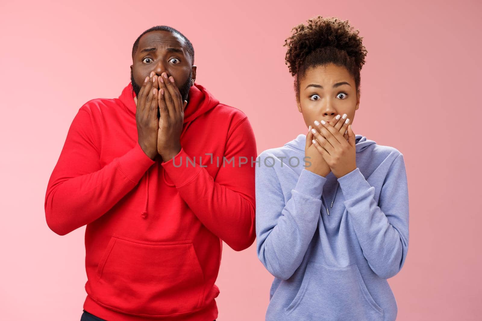 Two shocked african-american man woman widen eyes concerned terribly sorry press palms mouth gasping witness disaster hear sad bad news, standing worried pink background sympathizing friend by Benzoix