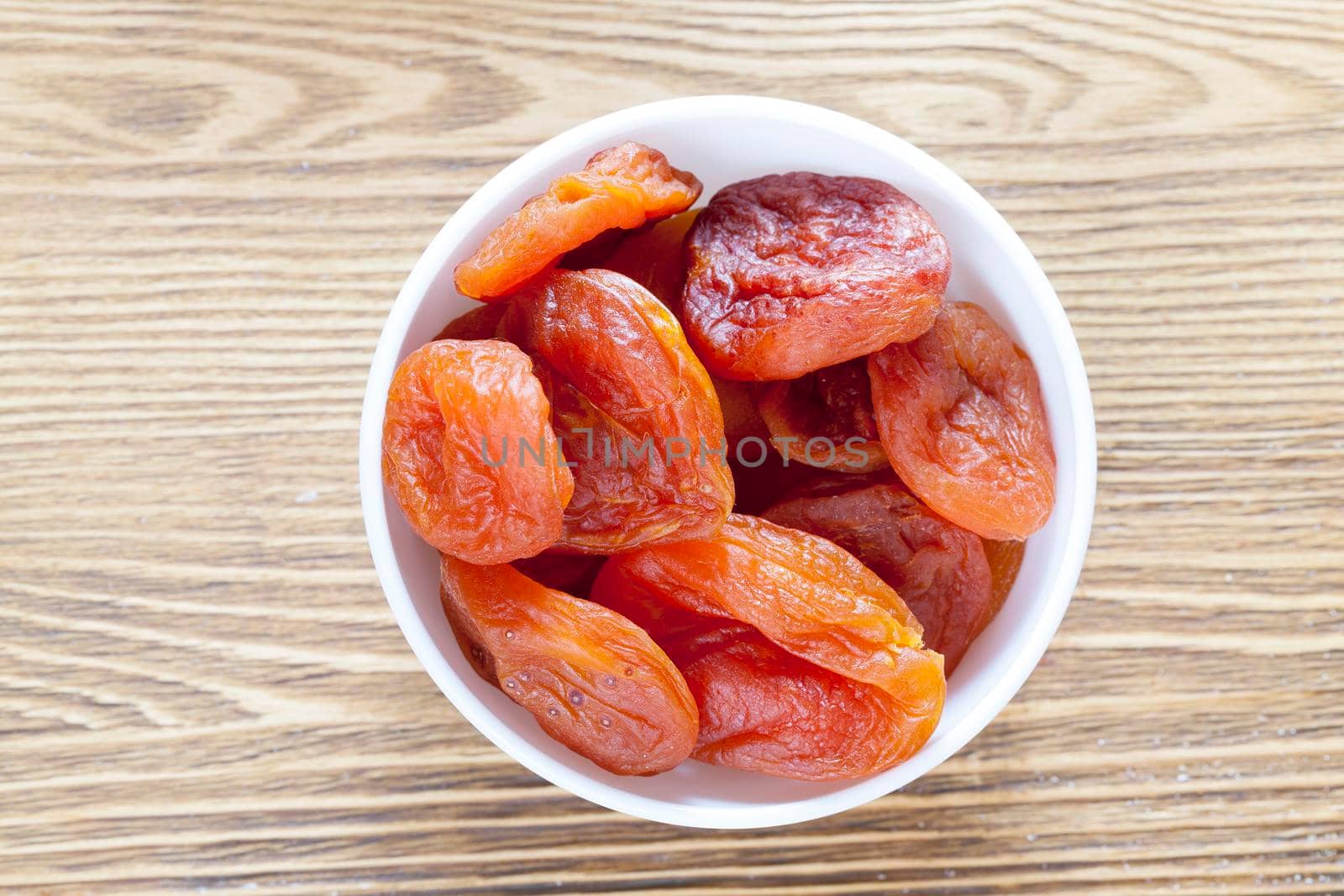 dried in a natural way, apricots lying in a white glass plate, closeup photo