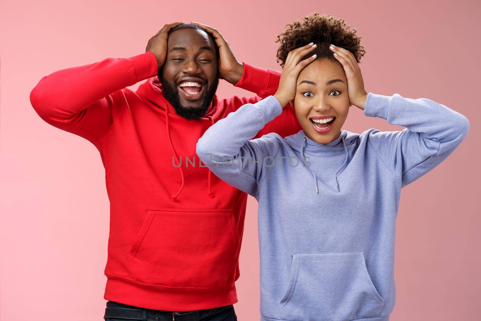 Waist-up happy charming surprised couple african american girlfriend boyfriend winning awesome gift lottery smiling impressed did not except win cannot believe luck grinning holding head shocked by Benzoix