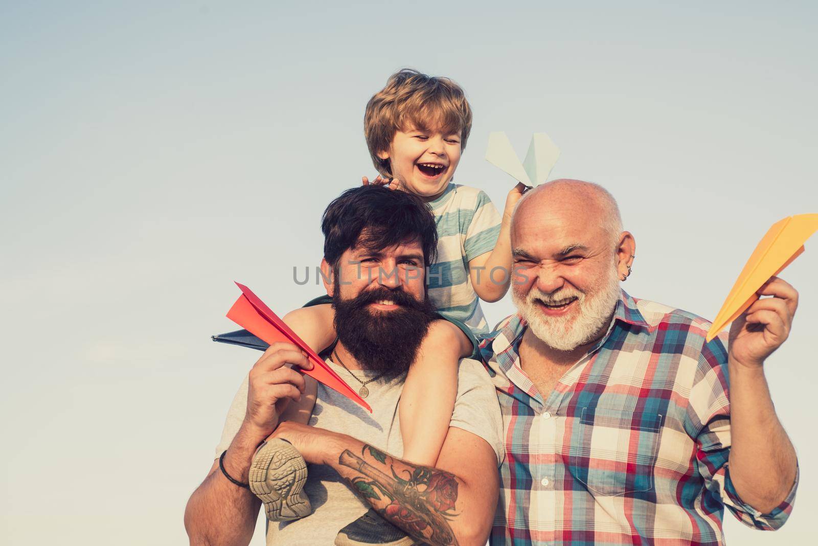 Weekend family play. Men in different ages. Leisure activity. Kid pilot with toy jetpack against sky background. Father son and grandfather playing - family time together. by Tverdokhlib