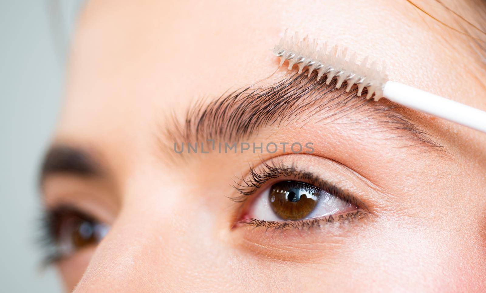 Eyebrows close up. Beautiful girl applies brow gel to her eyebrow. Close up portrait of young caucasian woman doing her eyebrow natural make up. Professional eyebrow make up concept