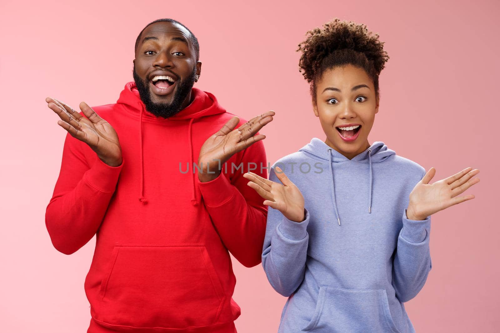 Impressed happy thrilled young pair african man woman relationship clapping palms joyfully surprised wide eyes joyfully greeting friends inviting come in hospitable, standing pink background by Benzoix