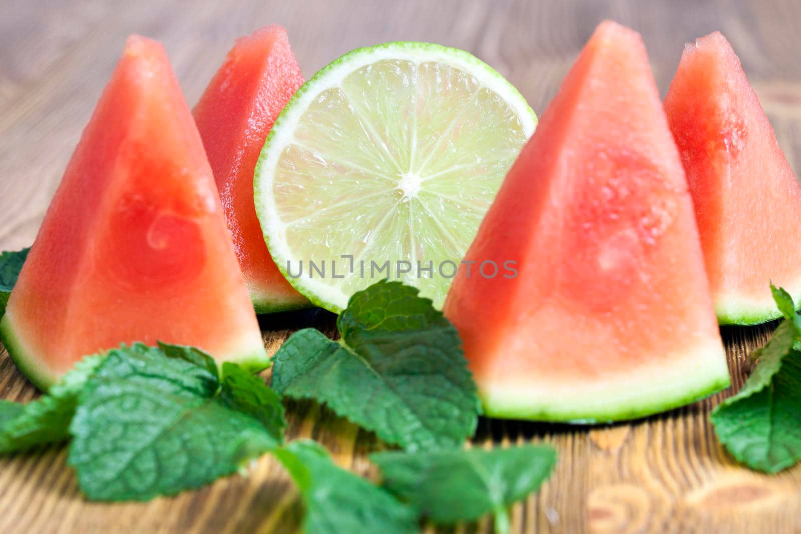 pink watermelon slices together with mint leaves and lime slice on the table