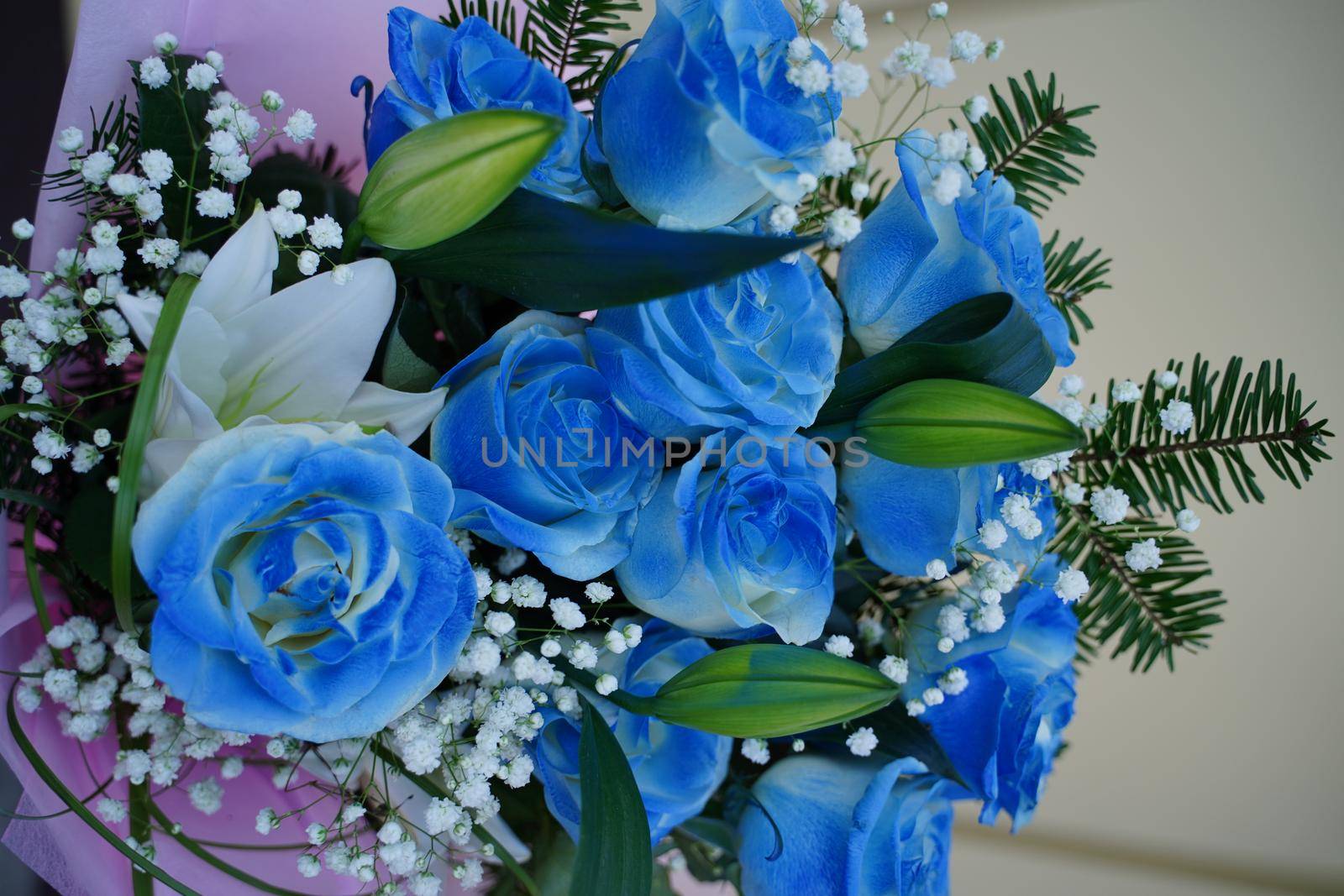 Close up of colorful bouquet of flowers. Flower composition of blue roses and white lilies in wrapping paper