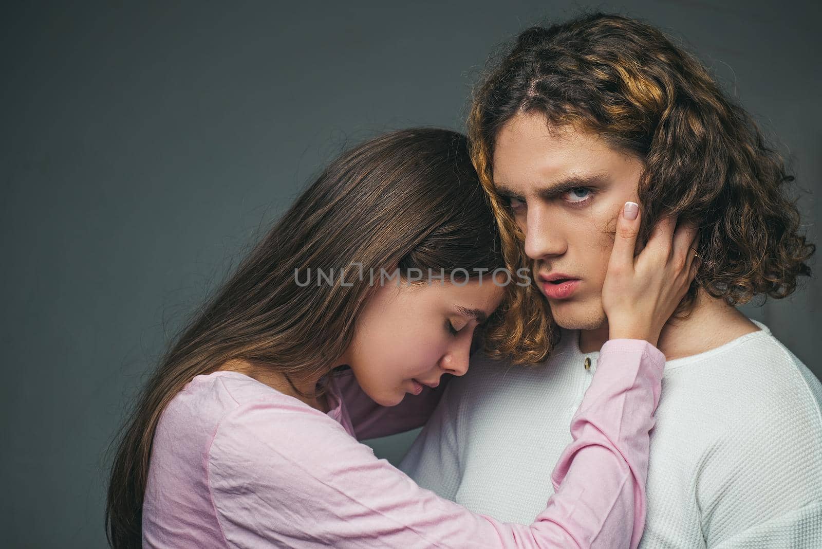 A beautiful young couple hugging and holding each other in the studio. We are better when we together. Love concept. Romantic and love. Attractive young couple hugging each other on grey background