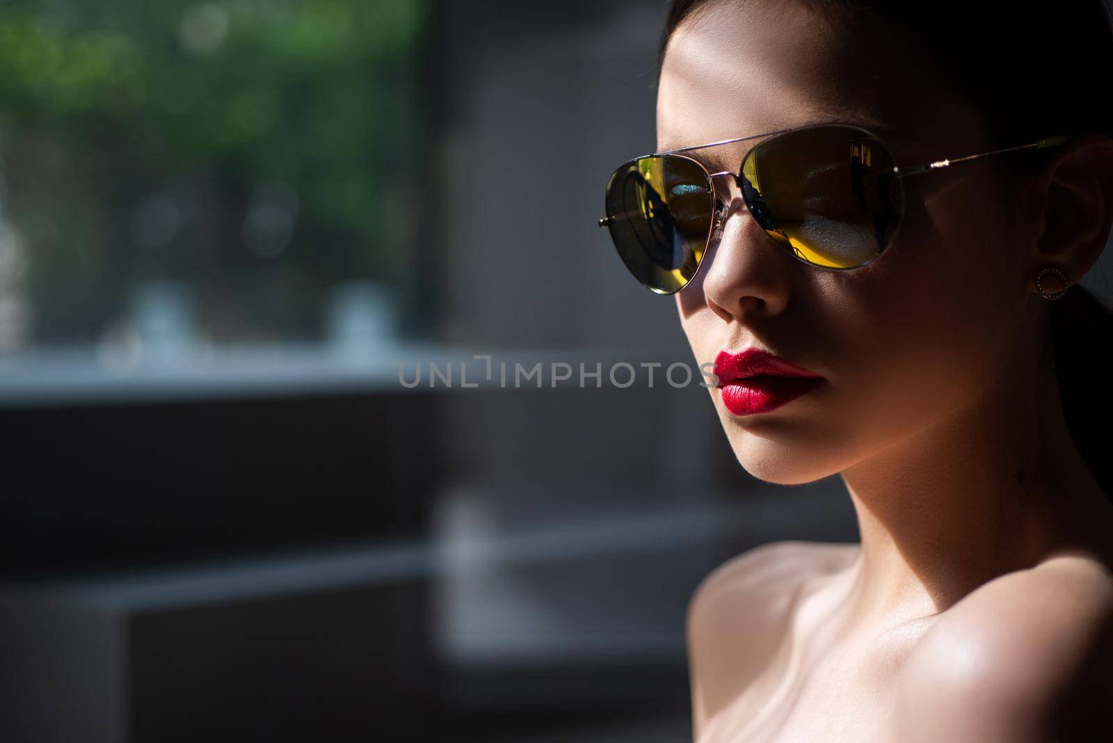 Female fashion model posing with sunglasses. Sexy. Close-up portrait of a beautiful charming young attractive woman in a sunglasses. Portrait of serious desire woman. Beauty trends. Dark background