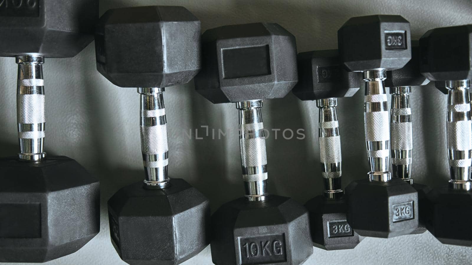 Close up of many metal black dumbbells on the floor at gym. Weight training equipment. Dumbbell set