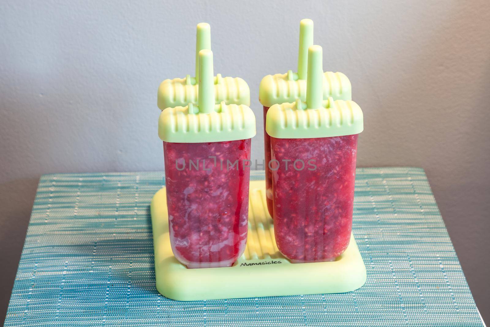 Homemade raspberry popsicles in a green mold during the summer heat.