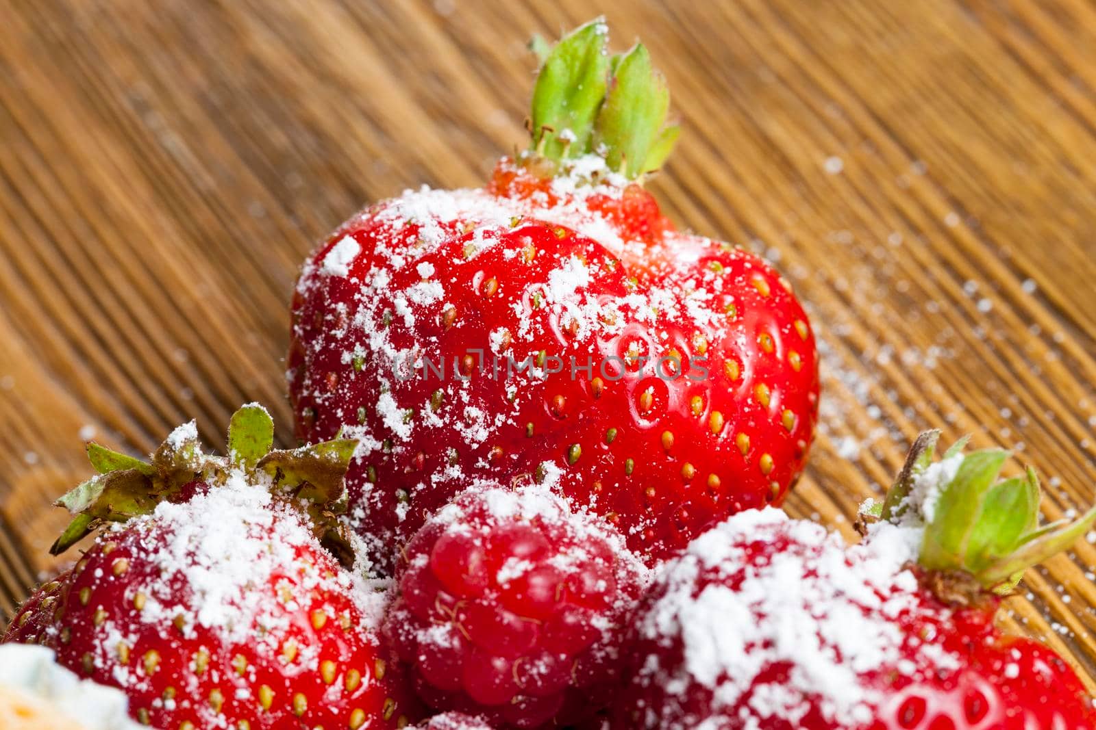 sprinkled with powdered sugar ripe red strawberry berries, lying on a wooden table while cooking