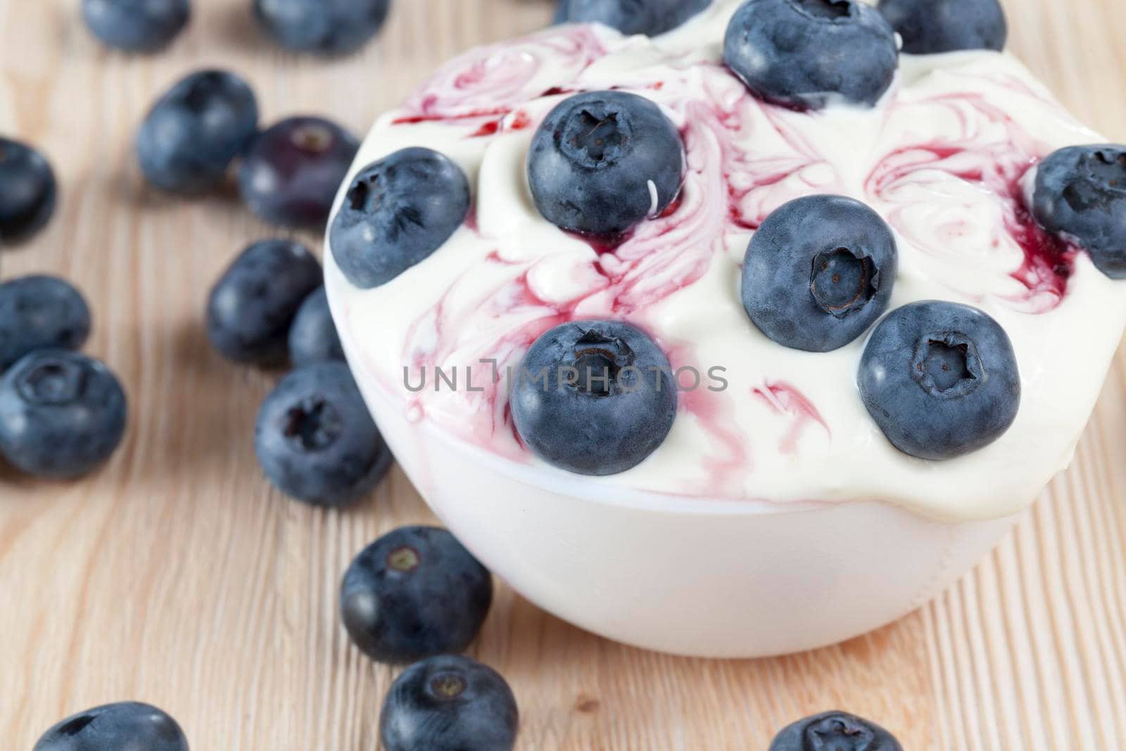 berries blue bog, cream or sour cream and blueberry jam, used during the preparation of dessert, closeup