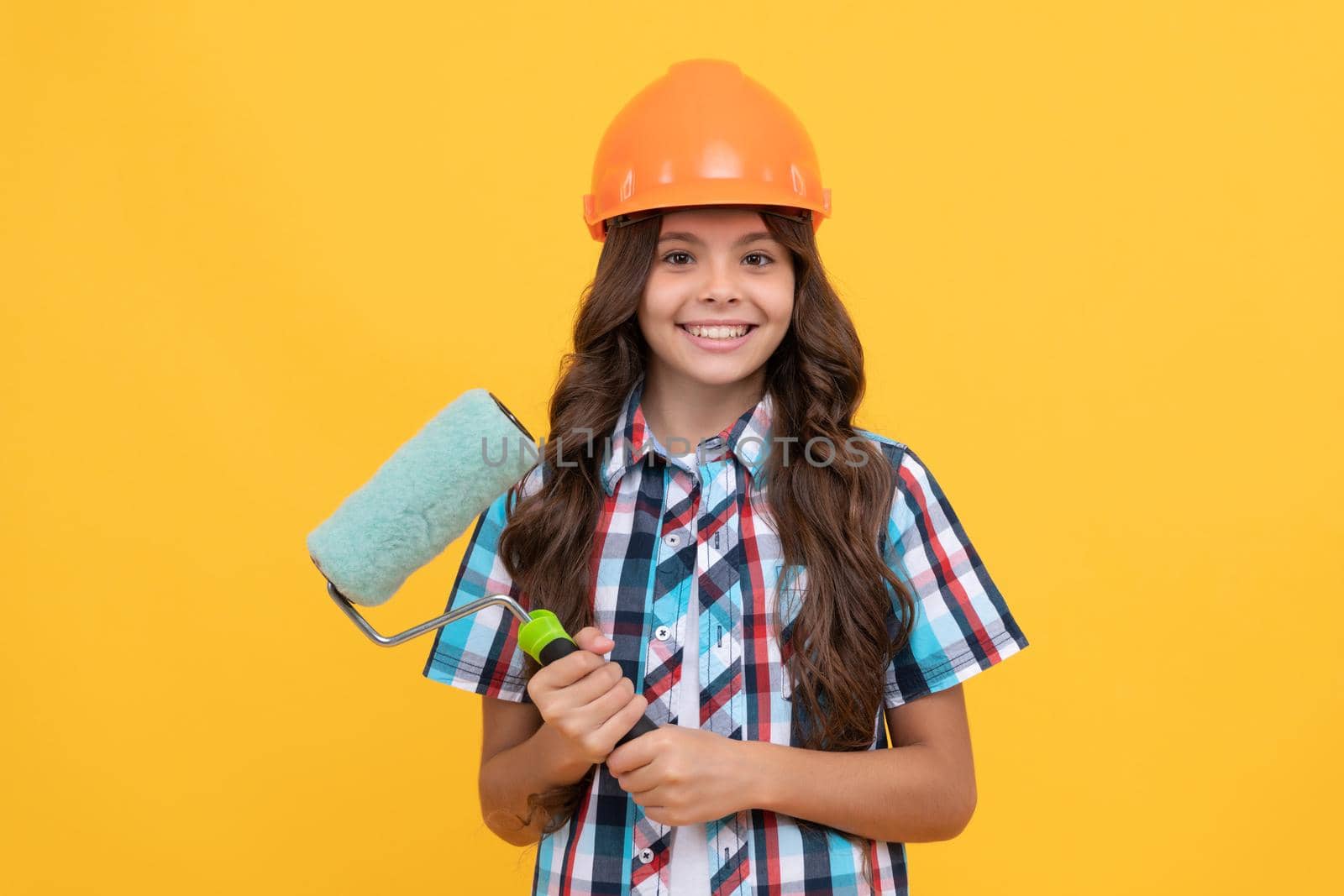 making surface repair. happy teen girl hold paint roller. child in helmet. roller brush for decoration. kid education. renovation work. improve your childhood. future renovator. improvement.