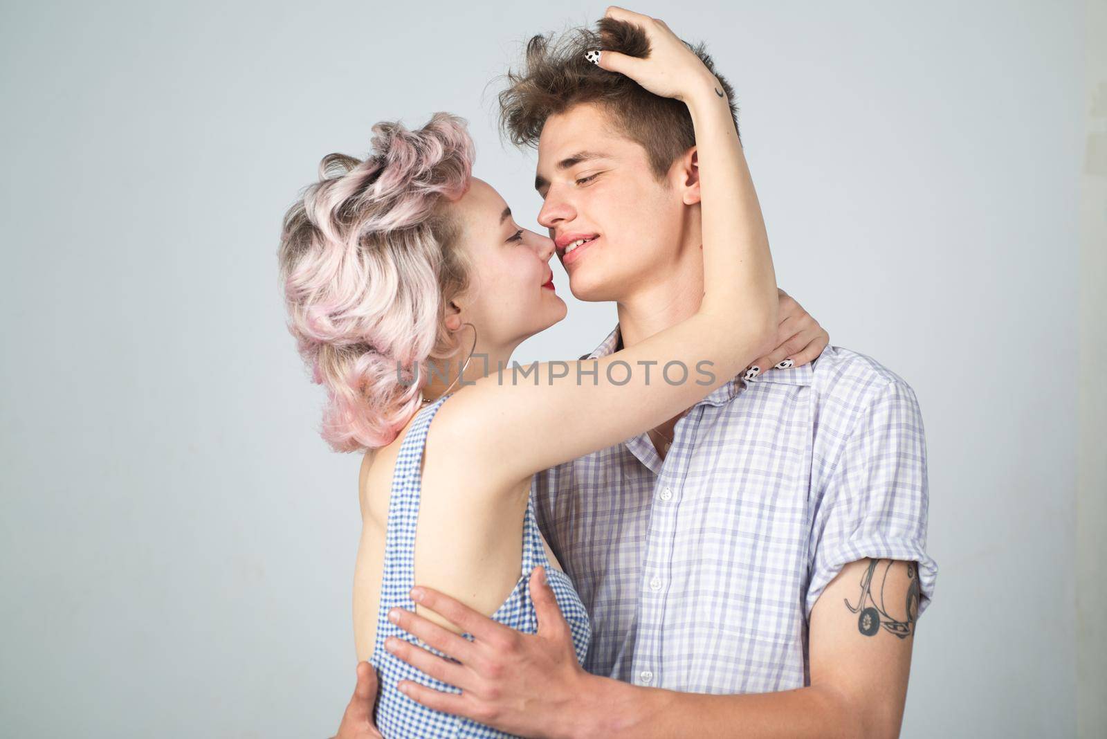 Young happy couple posing in studio.Gorgeous woman with long blond hair posing with handsome brunette man with sportive muscular man. Valentines day. Beautiful playful woman want kiss man. by Tverdokhlib