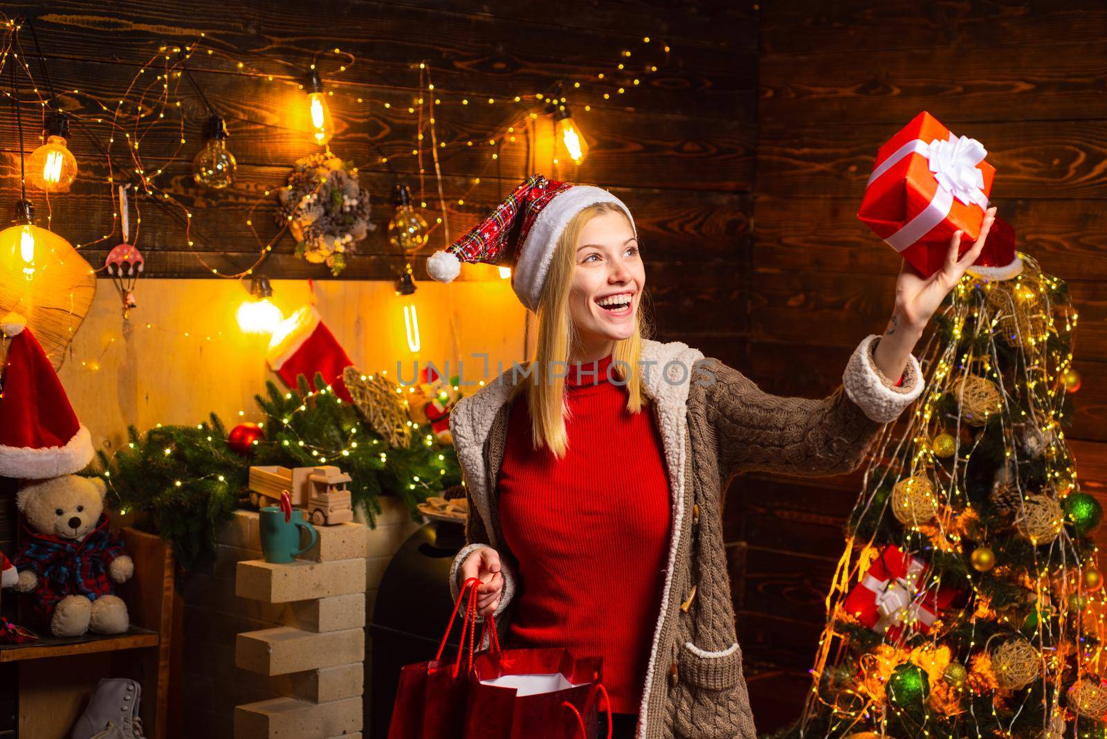 Young woman celebrates Christmas and holds her present gift. Xmas tree. Happy new year. Concept of Merry Christmas and New Year. New Year surprise present