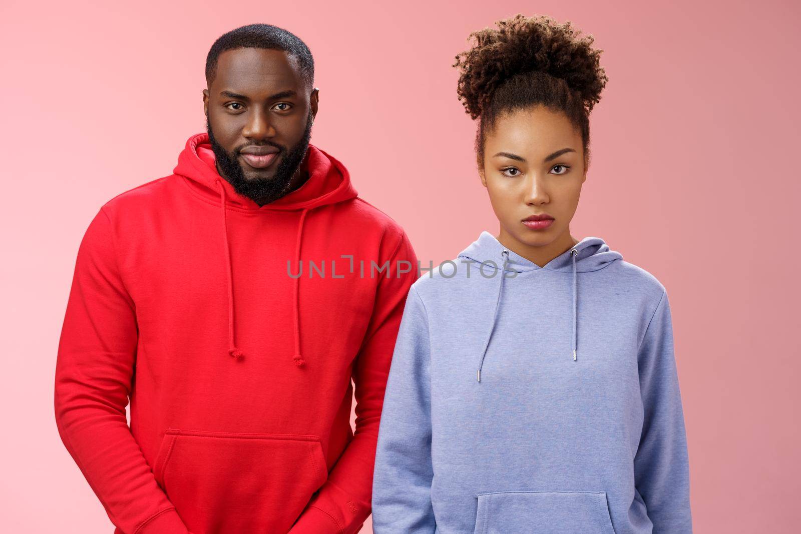 Two cute african american siblings standing together pink background invited family dinner greet new mom boyfriend, sister look displeased serious brother smug have idea prank stepdad by Benzoix