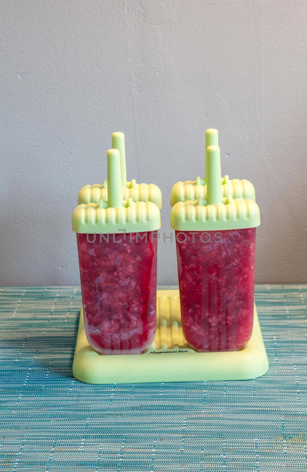 Homemade raspberry popsicles in a green mold during the summer heat.