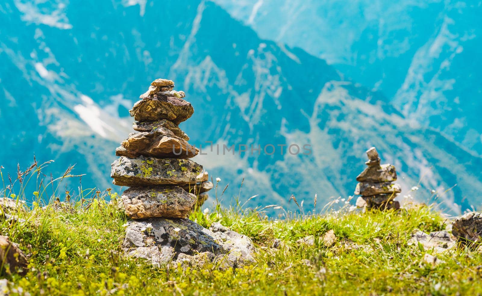 Close up of pile of stones on ground against mountain landscape. Decoration of stones on top of mountain on summer day. by epidemiks