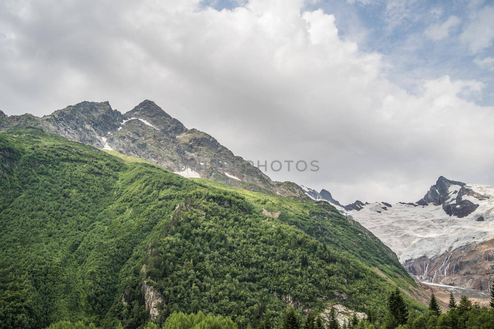 Peaks of magnificent rocks located against bright cloudy sky on sunny day in nature.