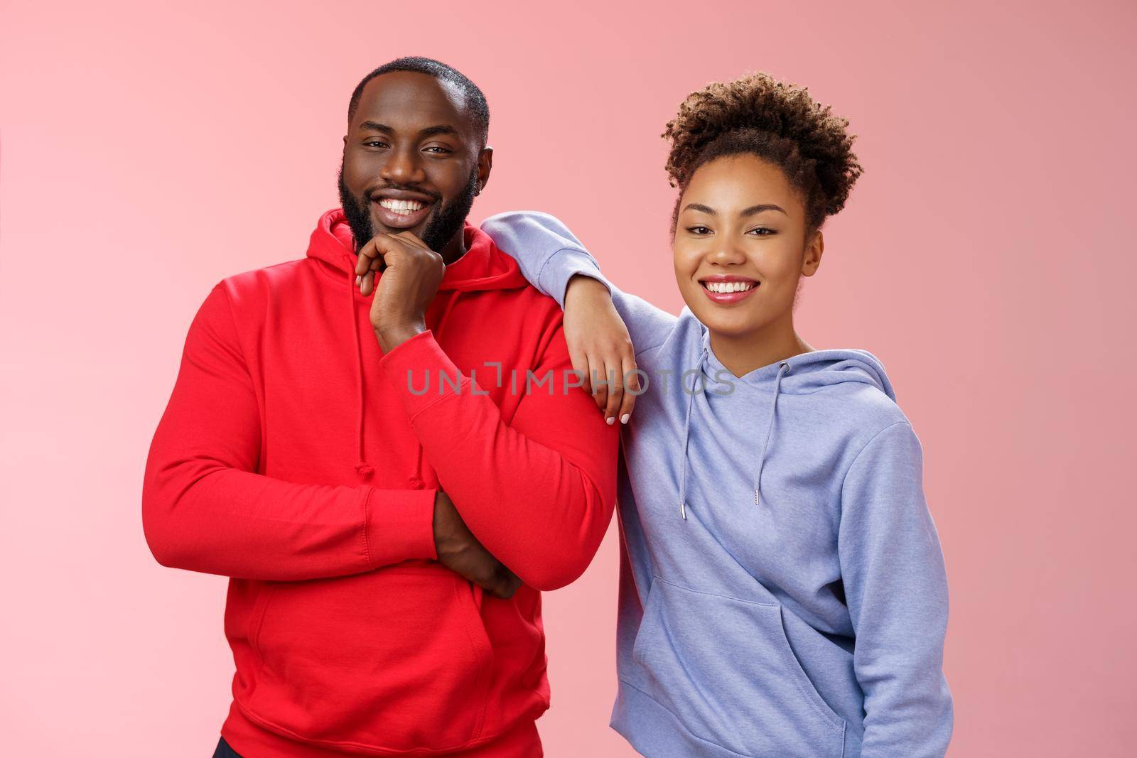 Romantic couple best friends standing pink background girl leaning boyfriend shoulder smiling broadly feel love respect each other working team standing pleased delighted friendly look camera.