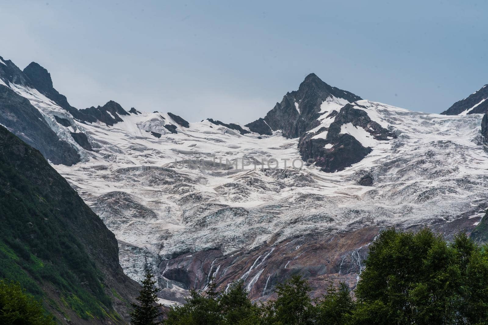 Beautiful landscape of glacier in summer season. Glacier mountain with green vegetation on high ground in cloudy weather. by epidemiks