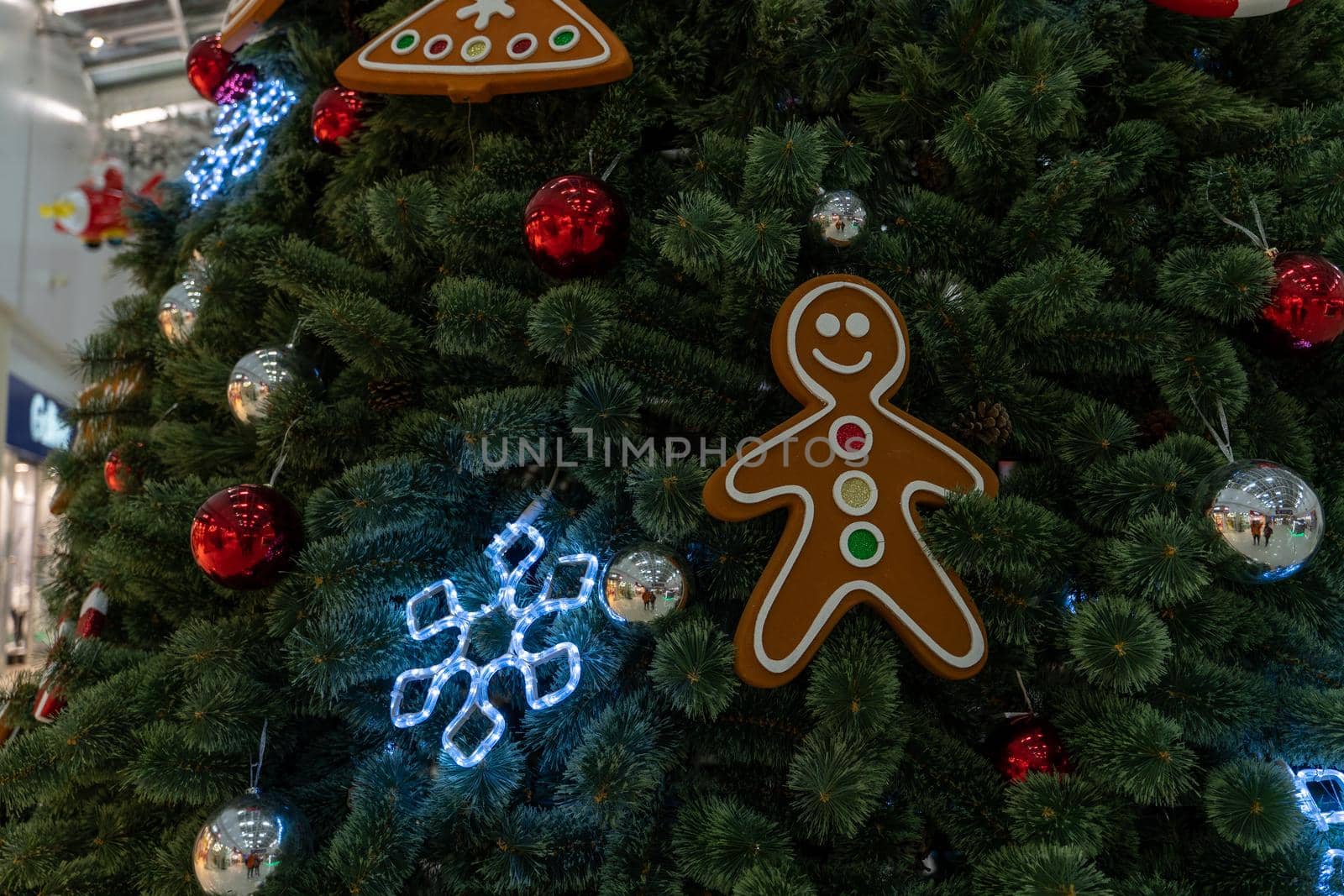 Close up of big Christmas tree with different christmas toys in shopping center. Coniferous tree with decorative adornments to create festive mood during holiday celebration. by epidemiks