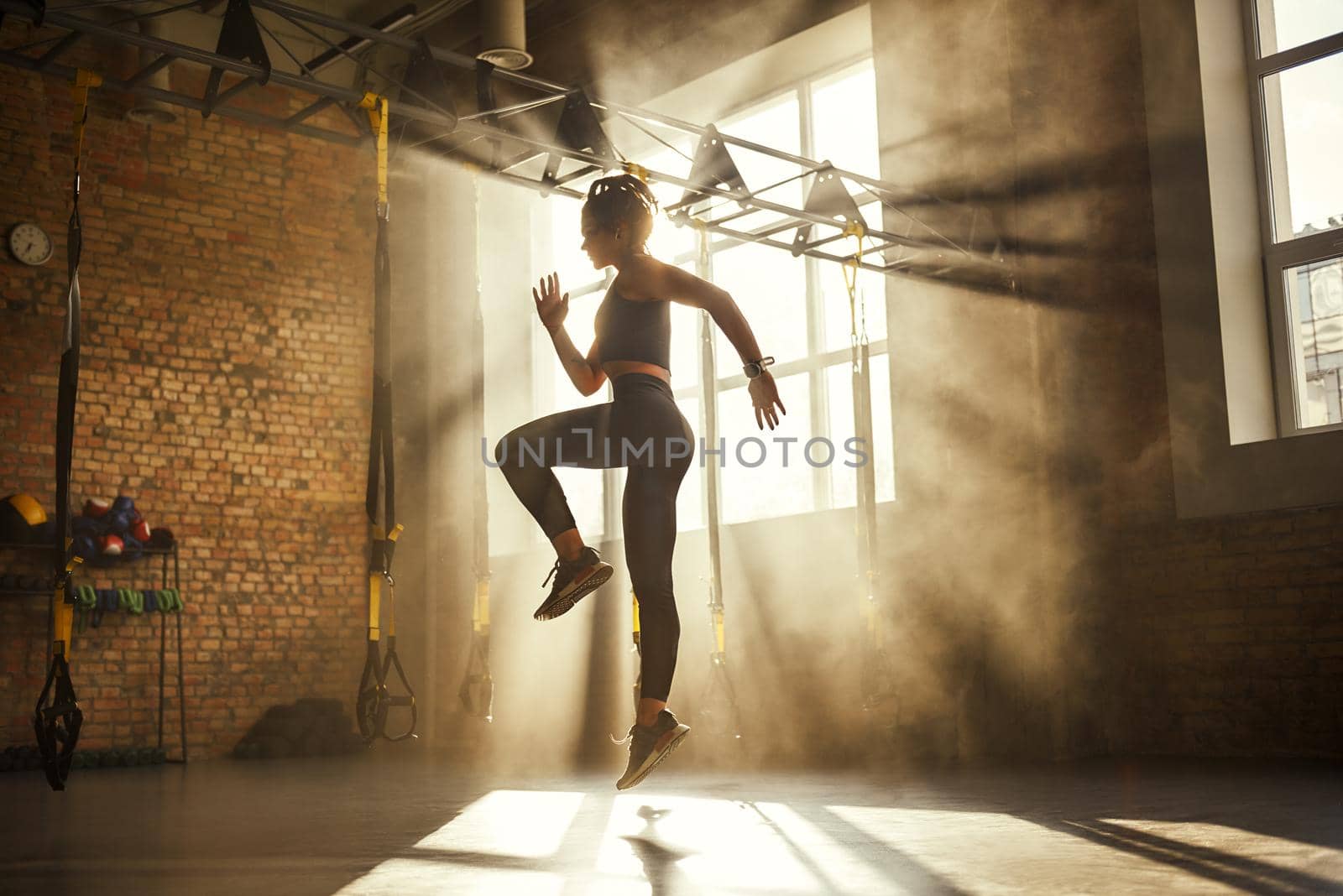Always in good shape Full length of athletic woman in black sport clothing exercising in professional gym. Professional sport. TRX Training. Workout