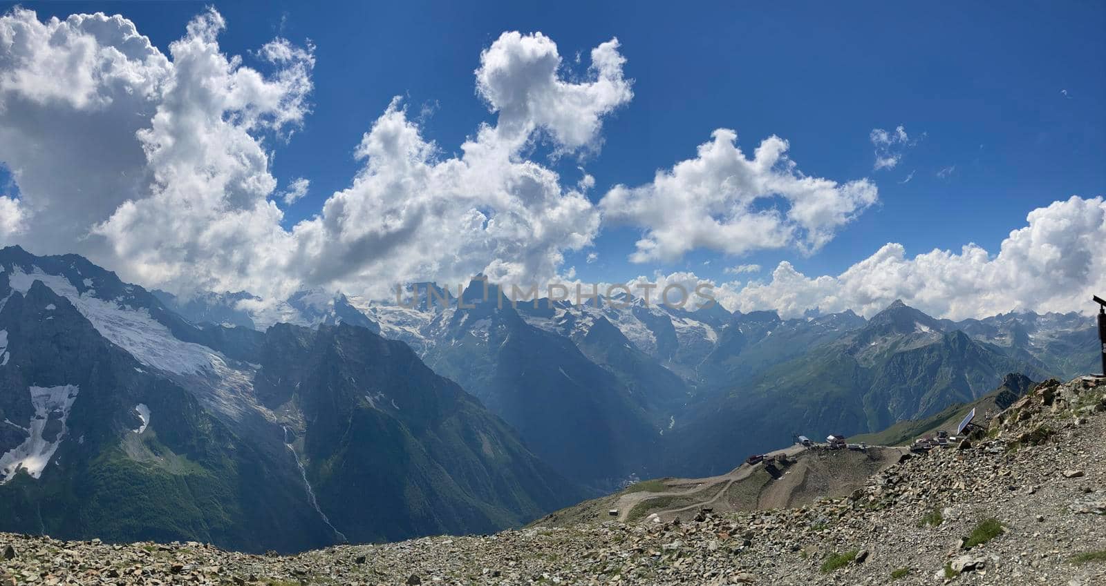 Snowy mountain against cloudy sky. From below white clouds floating on blue sky over mountain ridge covered with snow on sunny day in nature by epidemiks