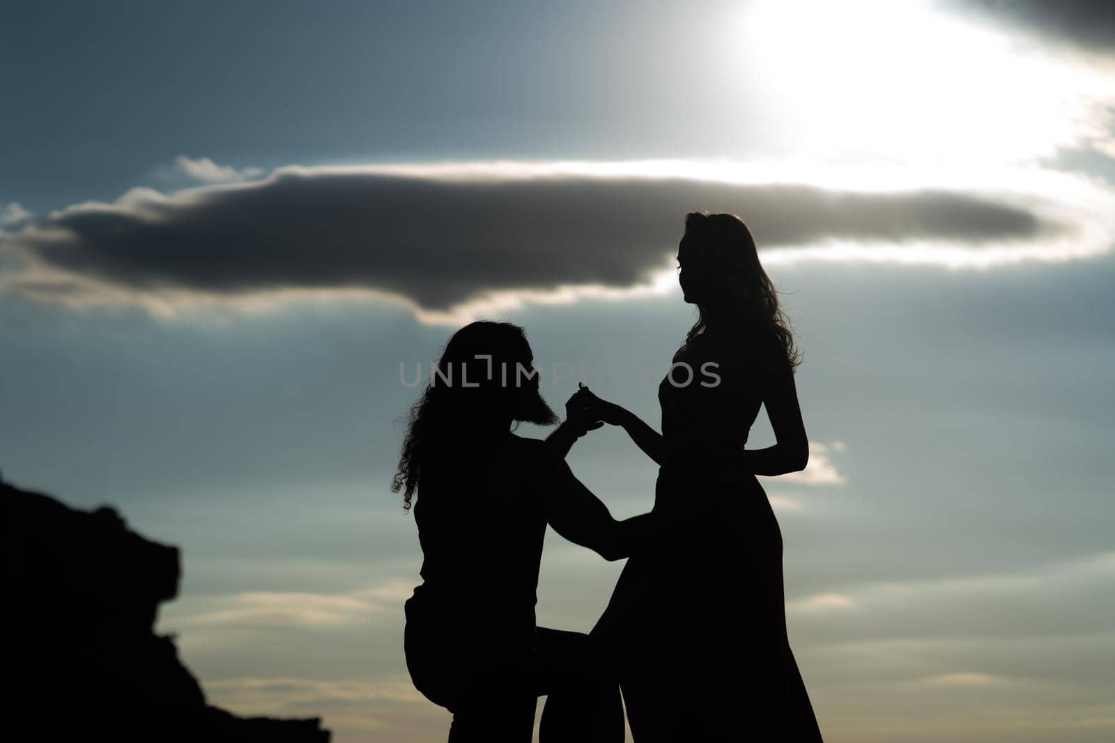 Shadow figures of man and woman holding hands. Love and relations. Silhouettes of love couple man and woman at rock mountain in beautiful nature sunset. Couple love concept