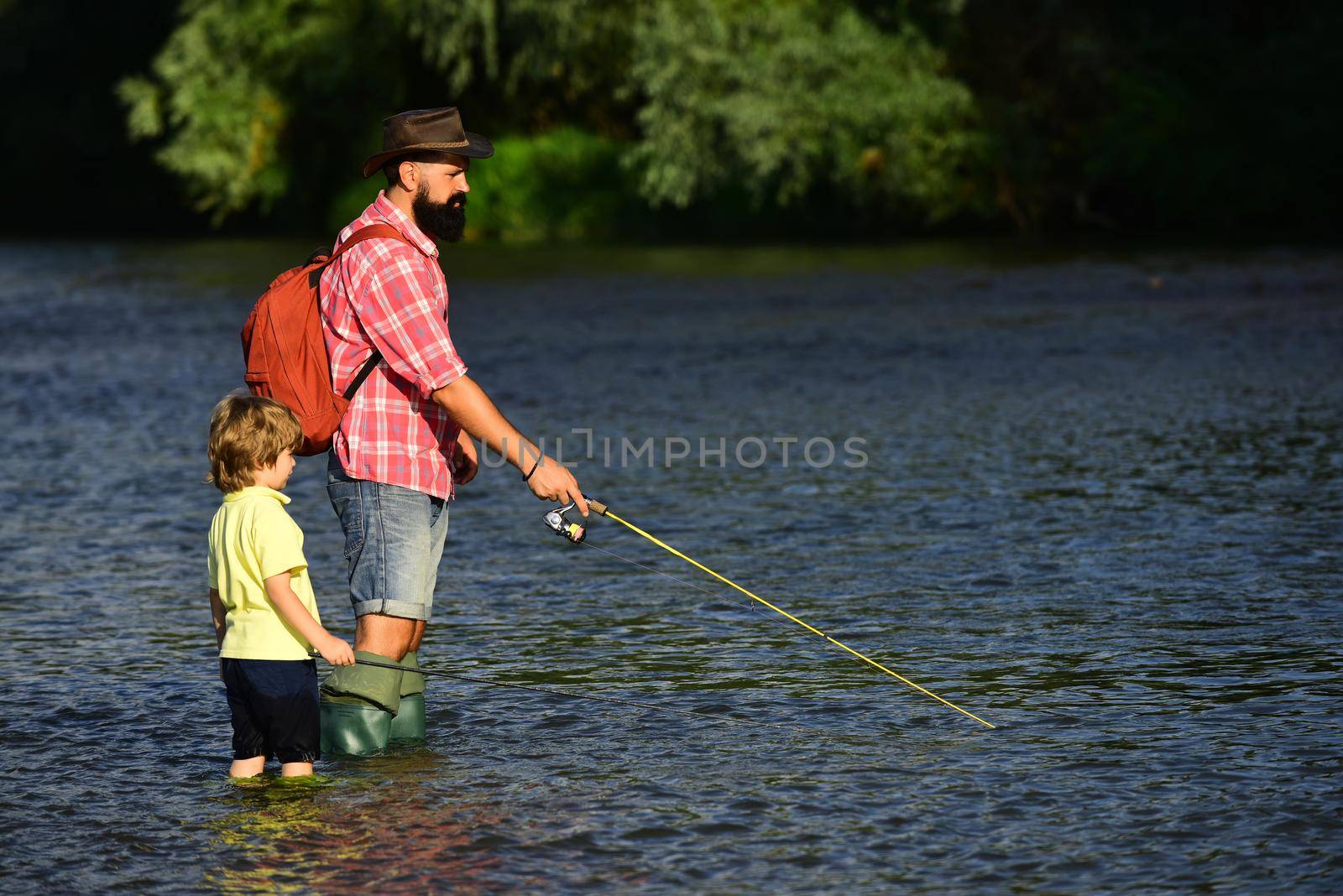 Dad and his child son are fishing on sky background. Brown trout fish. Fly fishing for trout. Generations men. Fishing became a popular recreational activity