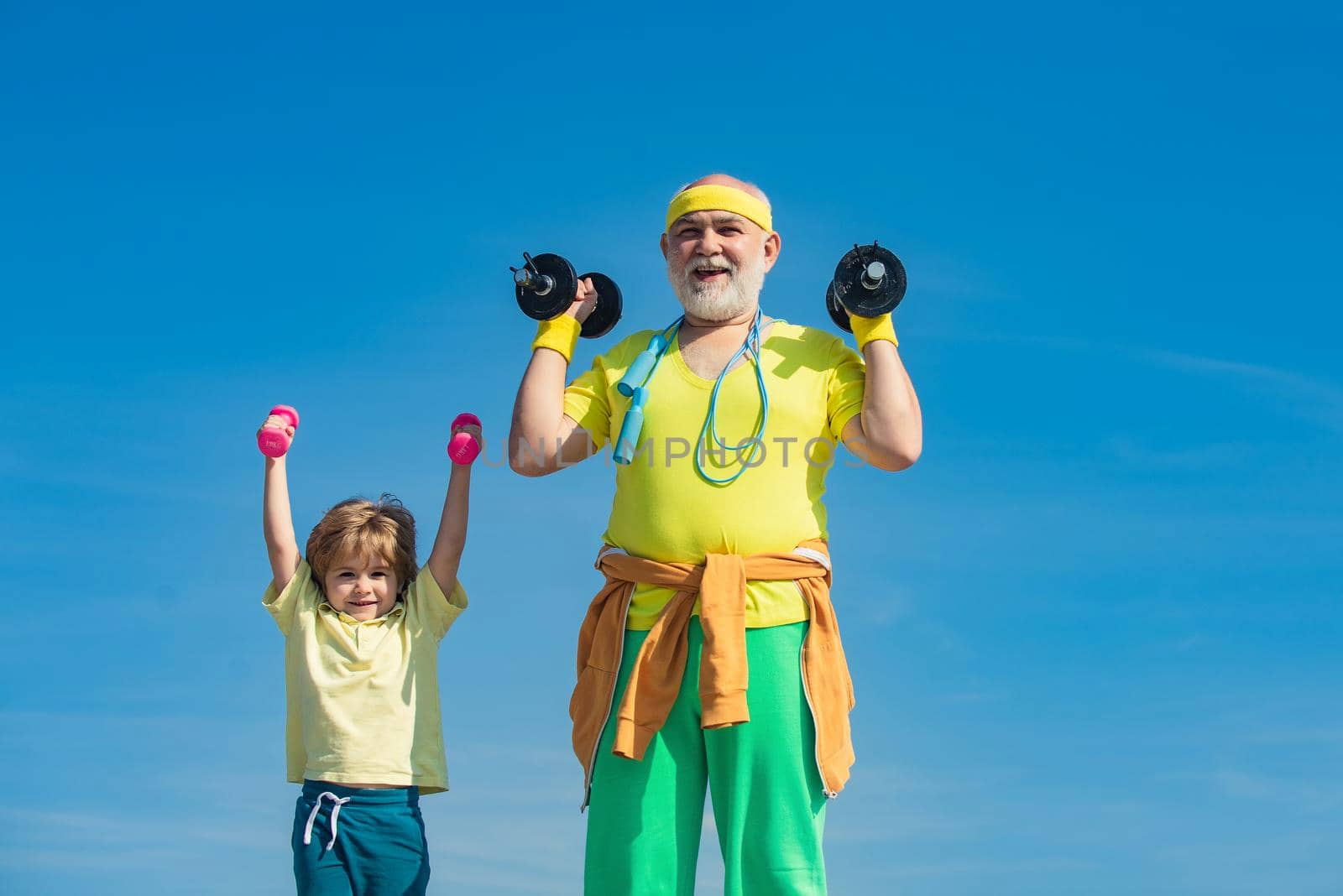 Age is no excuse to slack on your health. Healthy life and sport concept. Motivation and sport example concept. Portrait of senior man and cute child lifting dumbbells