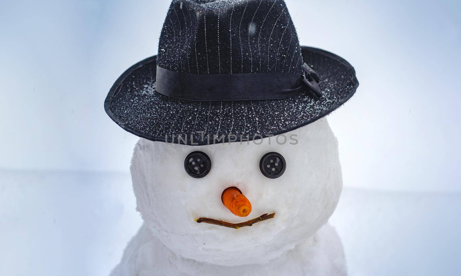 Snowman on a background snow-covered fir branches. Handmade snowman in the snow outdoor. Merry Christmas and Happy new year. Happy winter time