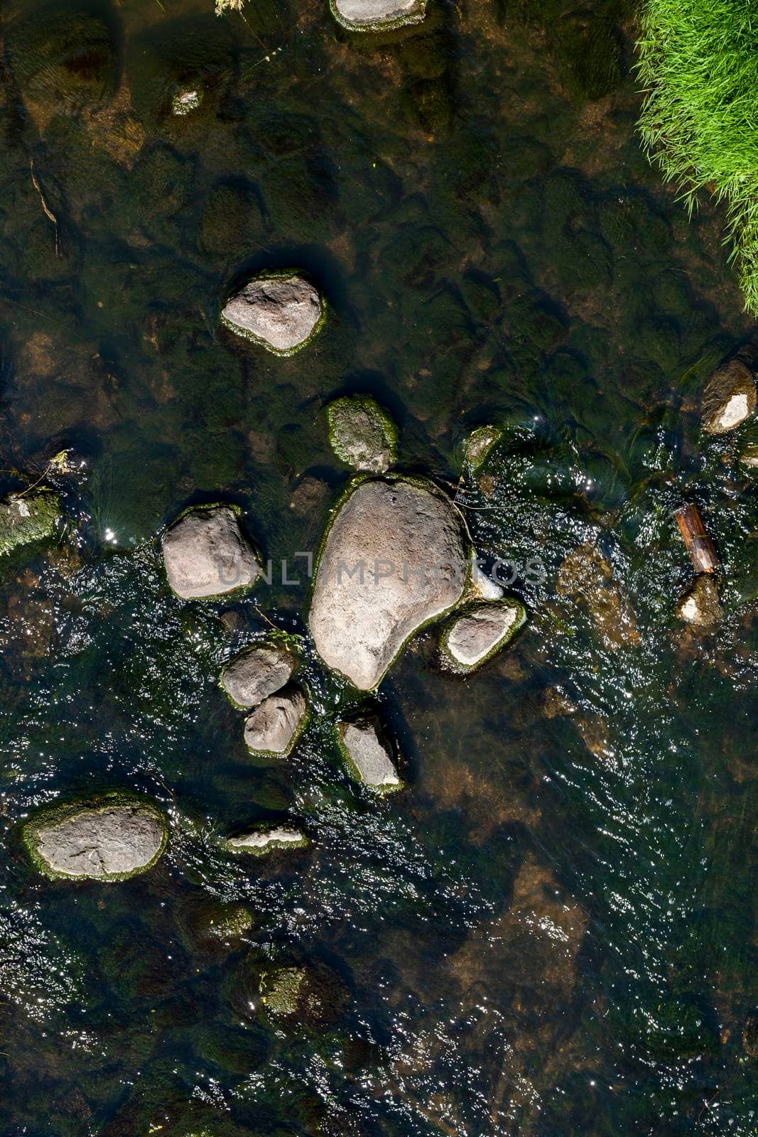 A small river with dark water in the middle of which lies stones and cobblestones, close-up photo