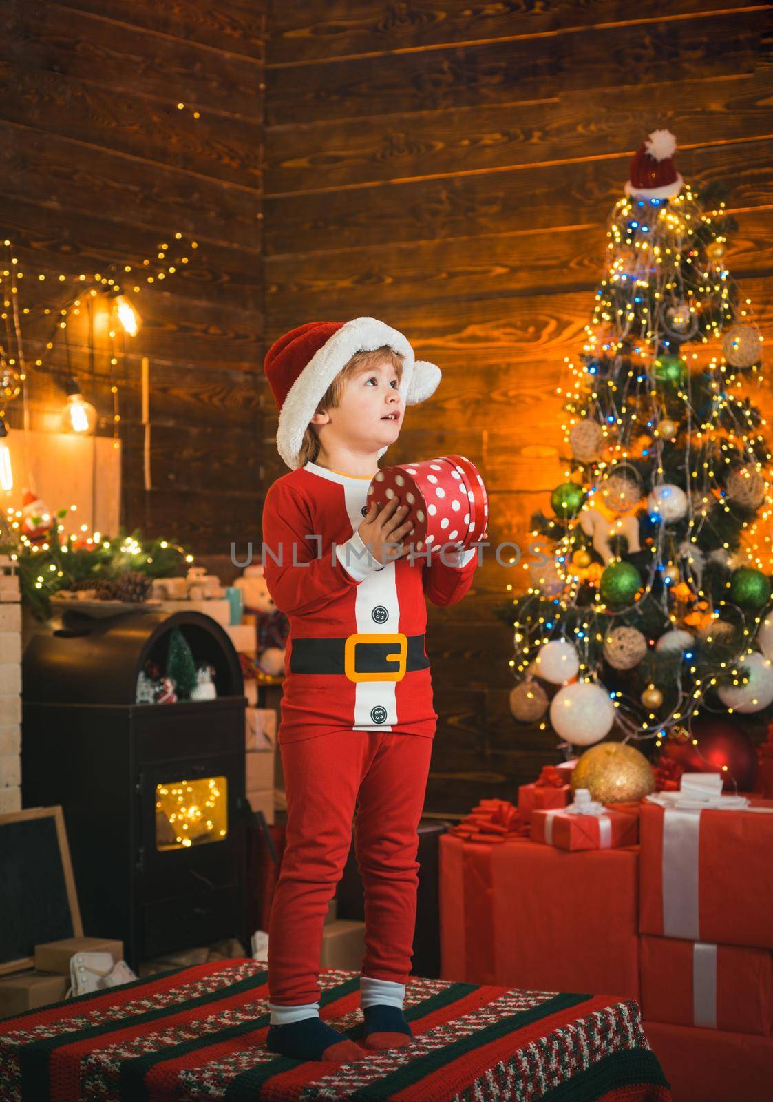 Bright New Years interior. Boy cute child cheerful mood play near Christmas tree. Indoor. Joy and happiness. Christmas shopping concept. Holidays and winter childhood concept