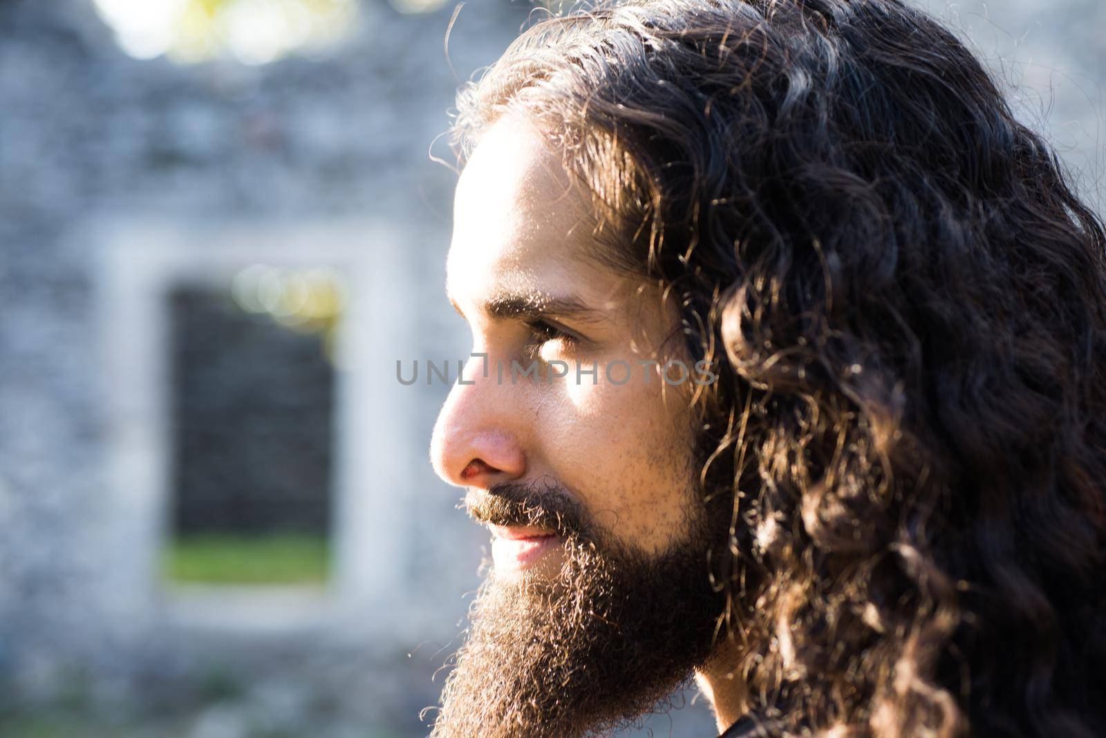Confident man with unusual appearance stare straight before one. Man style and fashion concept. Close up portrait of handsome man with long dark wavy hair and beard