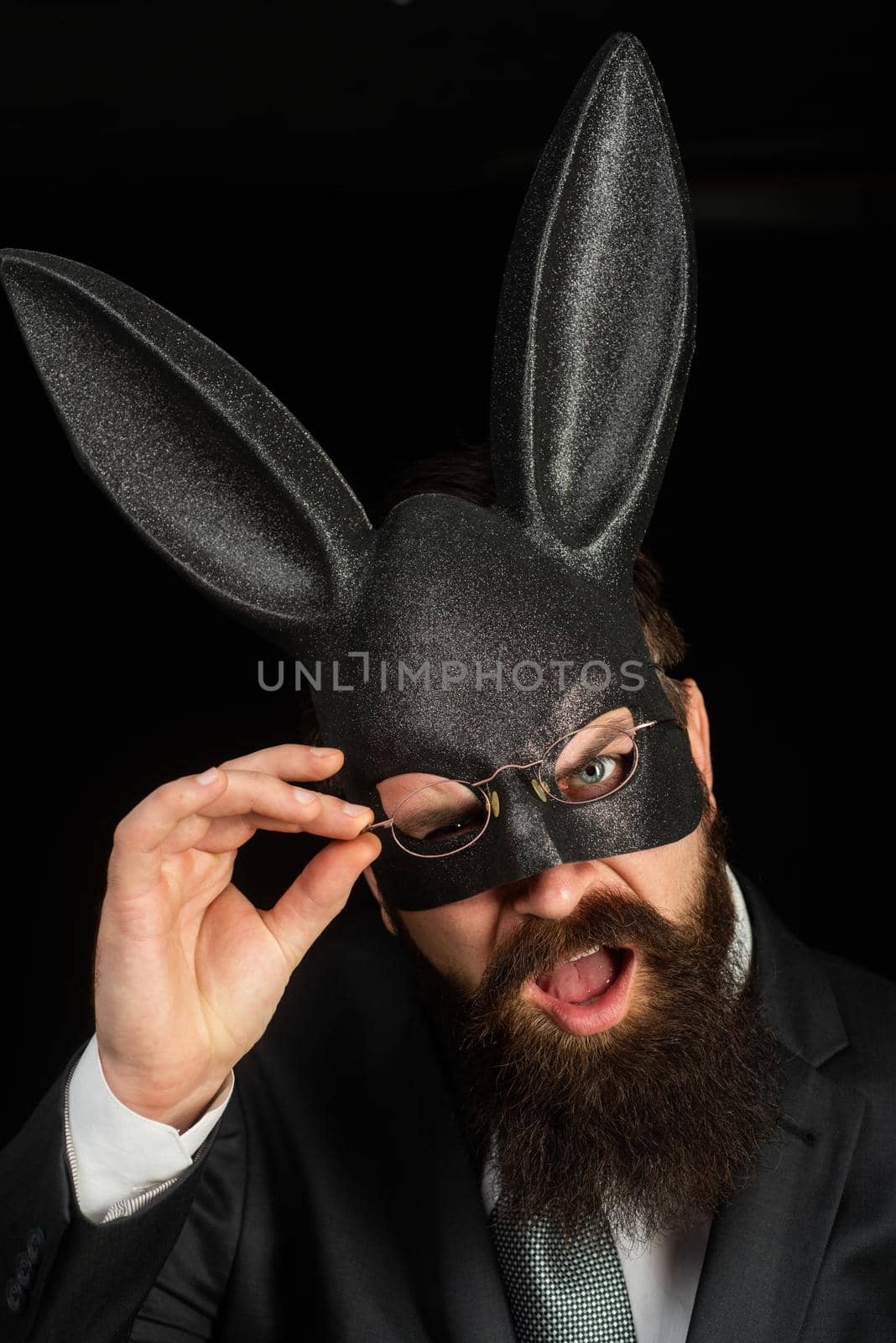 Funny bearded man in carnival rabbit mask. Bearded hipster in suit is ready for carnaval. Handsome man with beard in playboy mask