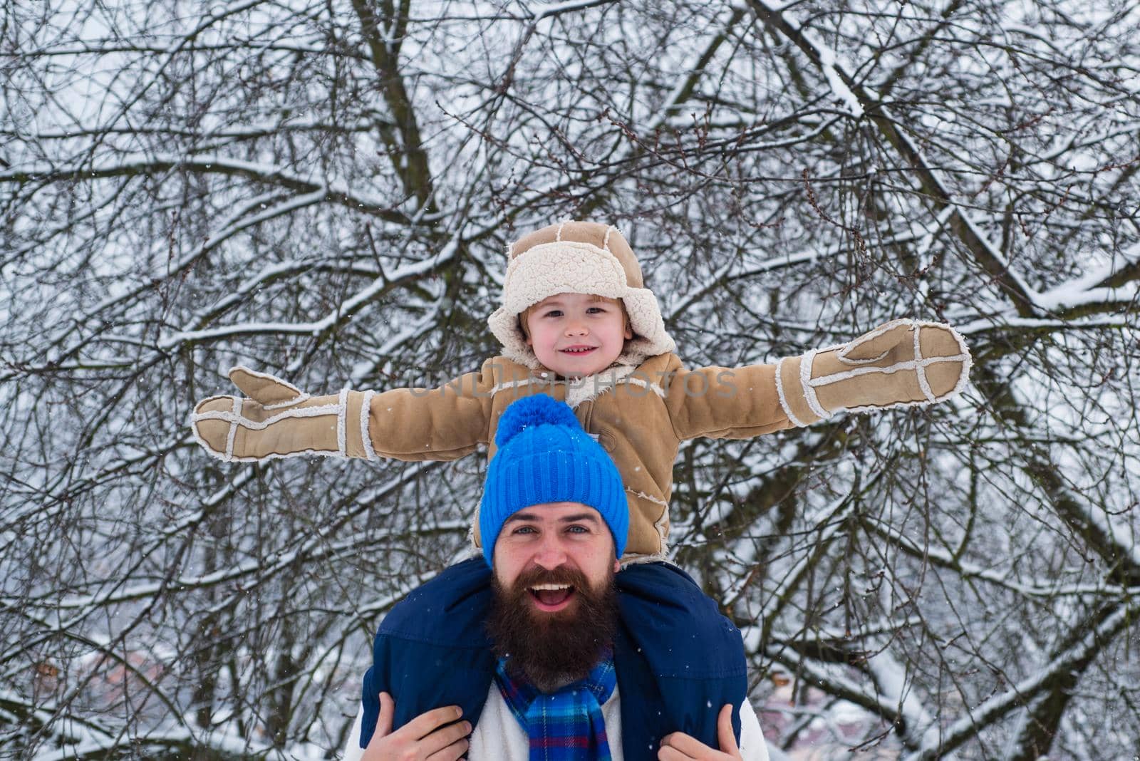 Child sits on the shoulders of his father. Father giving son ride on back in park. Merry Christmas and Happy new year. The morning before Christmas