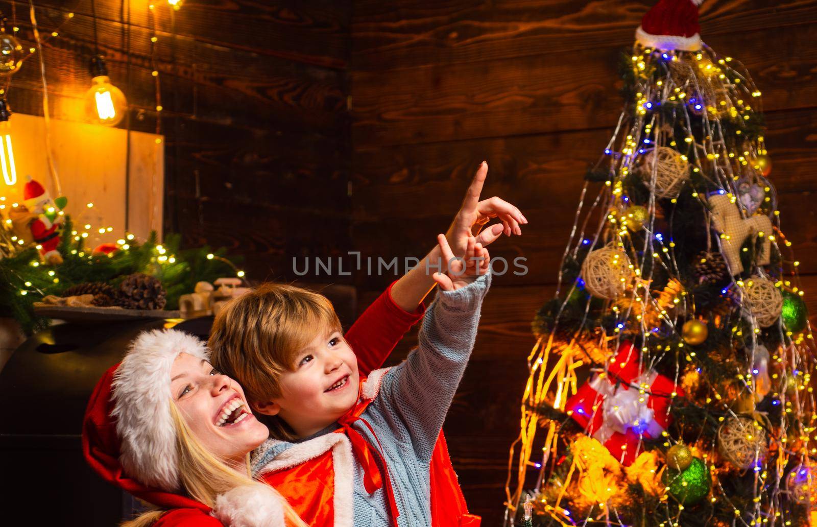 Happy new year. Childhood moments. Gifts for winter holidays at fire place. Christmas interior. Elf child. Portrait of happy mother and adorable baby celebrate Christmas