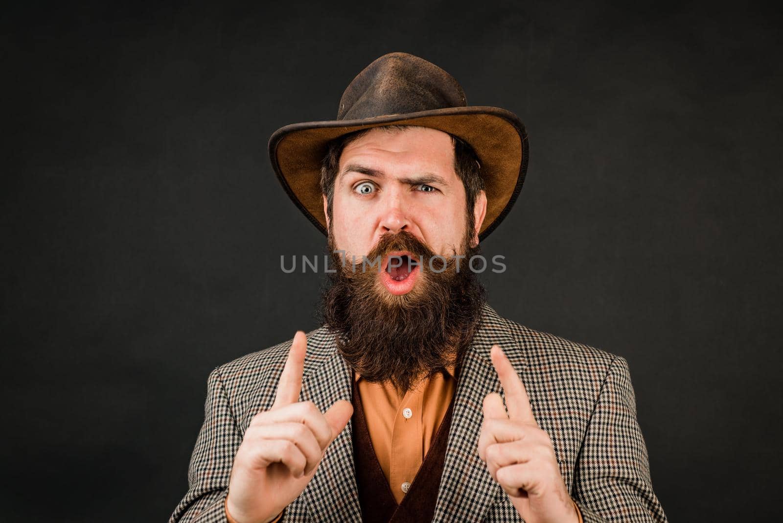 Funny brutal bearded hipster on isolated background. Close up photo of handsome funny man with beard in suit. Hand with fingers set into gun gesture