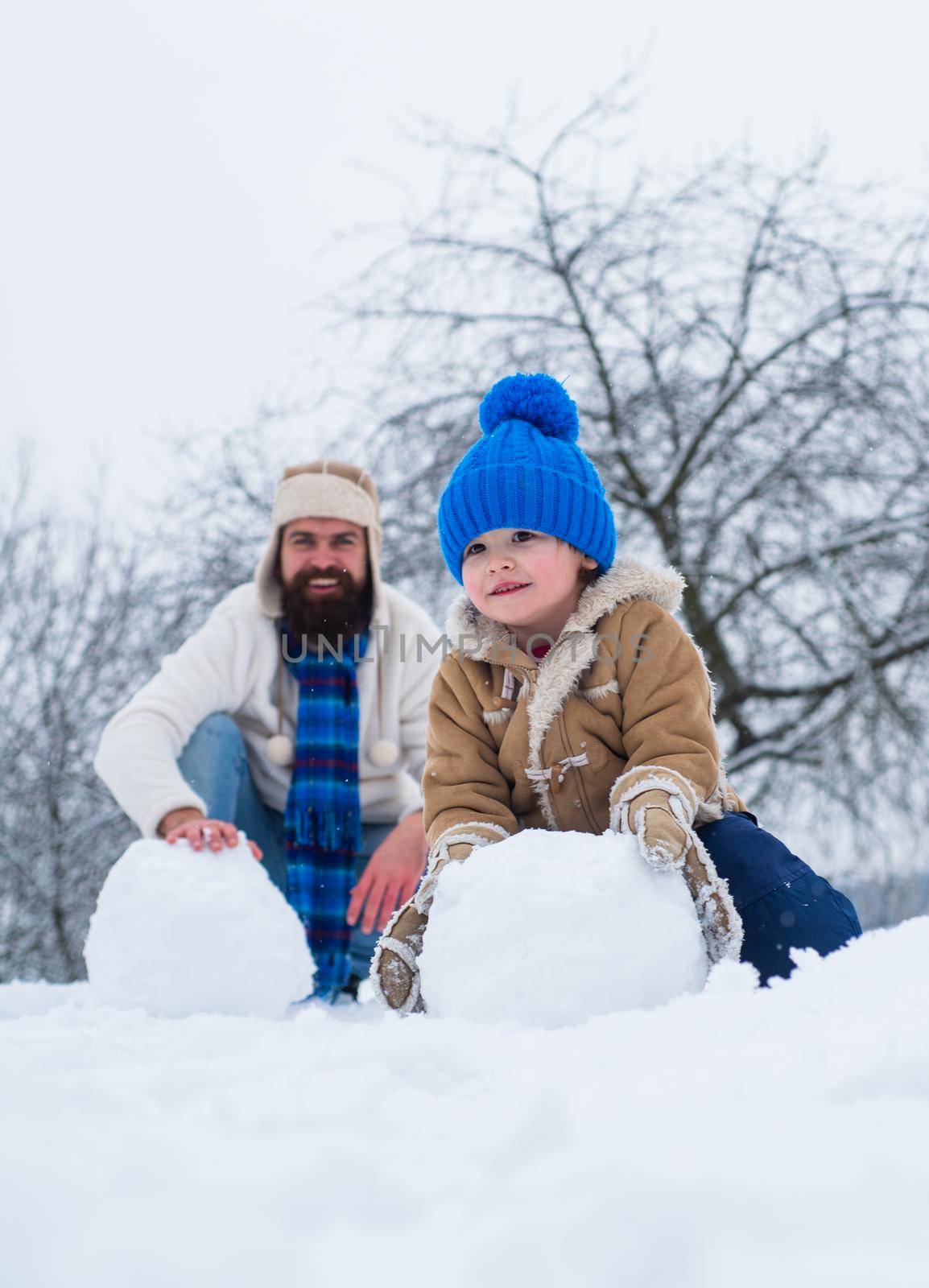 Happy father and son making snowball in the snow. Handmade funny snow man. Happy father and son play on winter Christmas time. Happy winter time. Father and son in snow. Fathers day