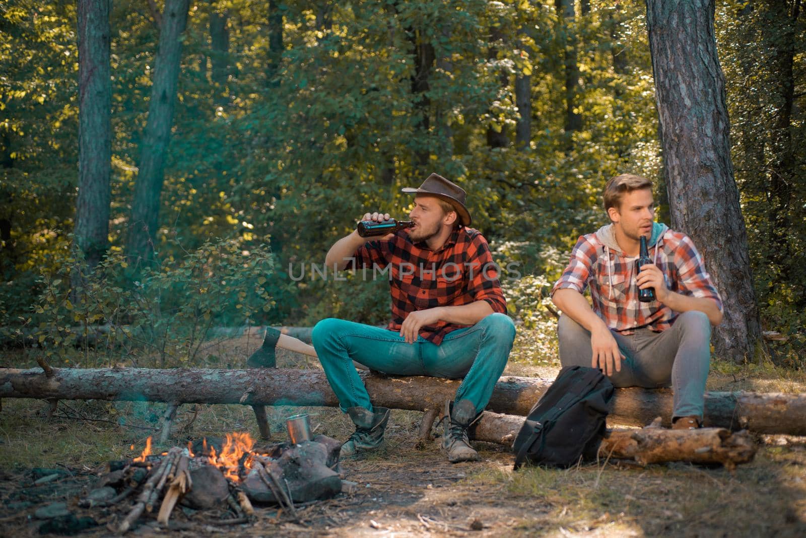 Friends having fun at camp fire. Young guy having a picnic. Young man having picnic in woods. Weekend. Friendship and leisure concept. Group of young people having fun outdoors