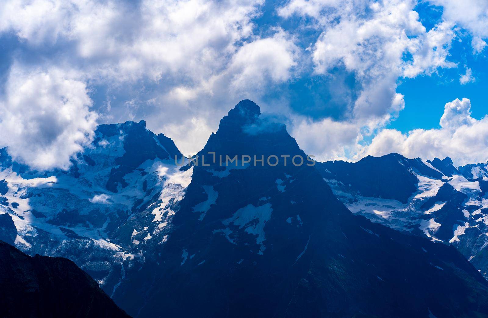 The rocky mountains were shrouded in clouds on a Sunny day.