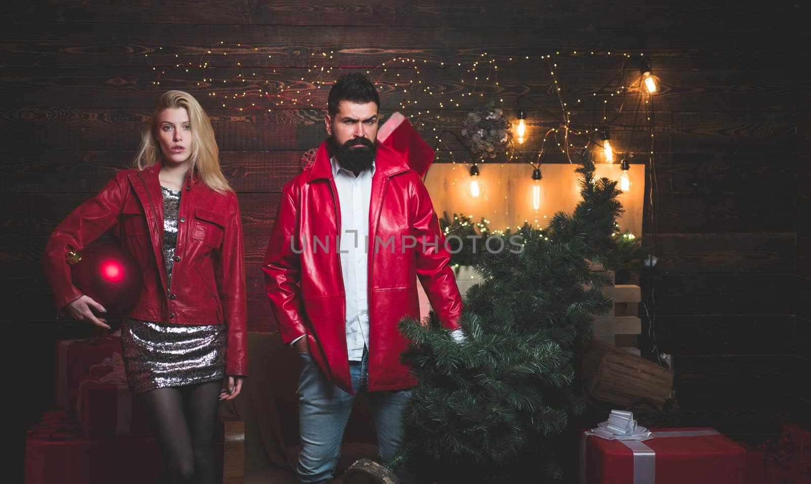 Christmas tree. Beautiful Couple dressed in a Santa hat. Handsome bearded hipster Santa with smiling positive young woman. Having a crazy day with friend