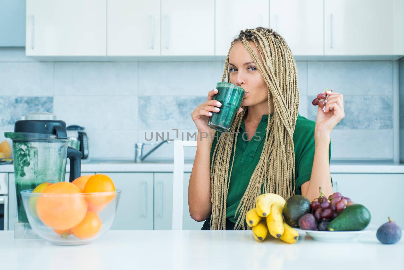 Detox. Female hand holding glass of fresh organic green smoothie with spinach. Fitness and dieting. organic food and vitamin. Athletic young woman with protein shake in kitchen