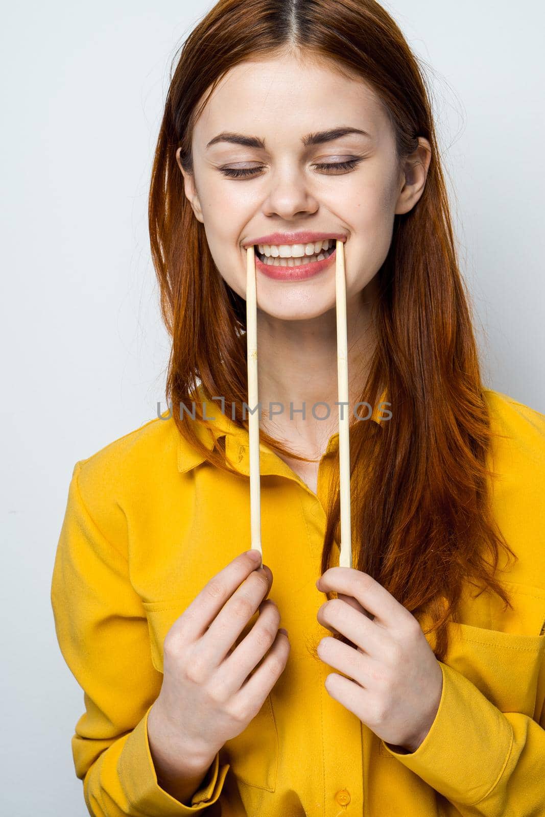 woman eating sushi with japanese chopsticks posing light background. High quality photo