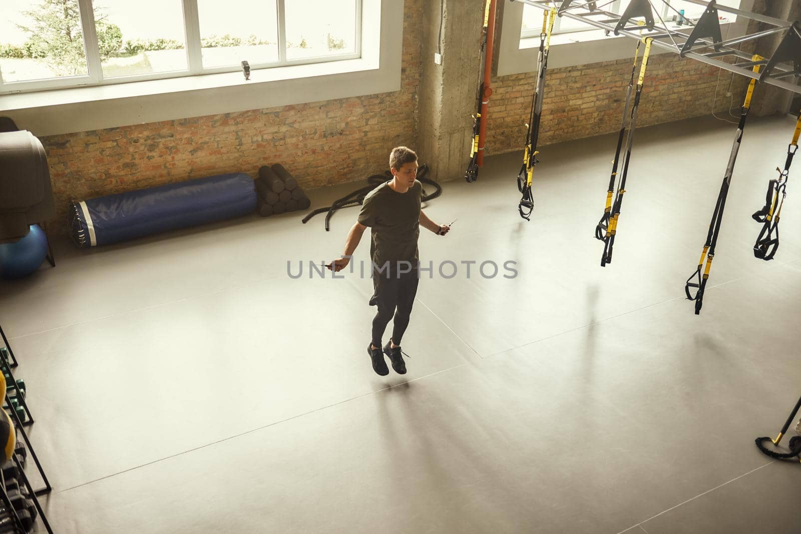 Full length of young sporty man is skipping rope while exercising at gym. Sport concept. Fitness. Active life